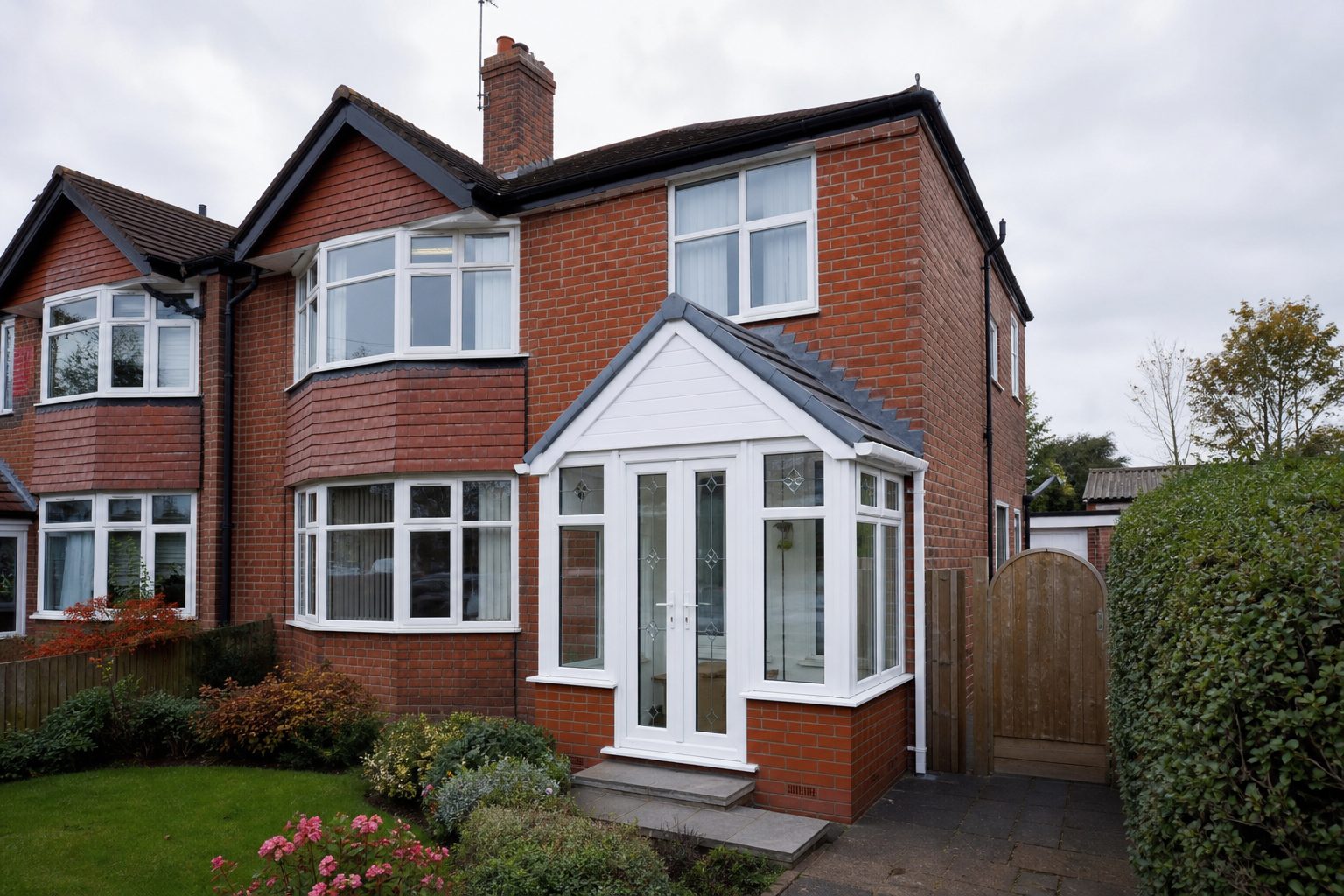 New white uPVC porch with a pitched tiled roof on a red-brick Teesside semi